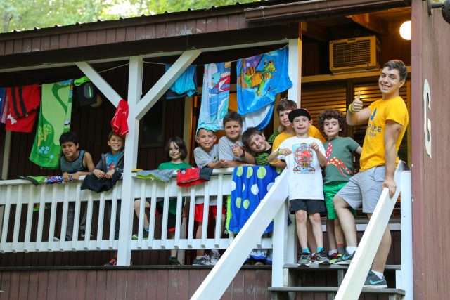 Group of young male campers hanging out on the balcony of their camper housing